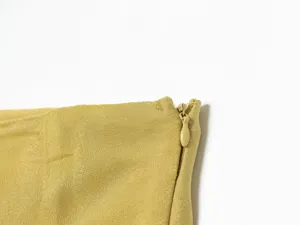 Detailed close-up of a yellow skirt zipper, showing fine fabric texture and neat stitching.