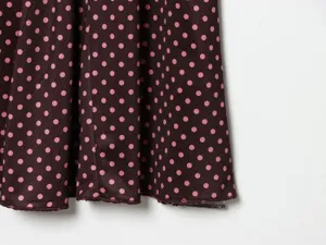 Close-up detail of women's brown polka dot fabric and hemline, stylish and elegant pattern.