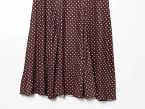Close-up detail view of a stylish brown midi skirt featuring cute pink polka dot pattern.