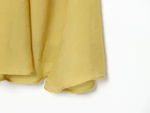 Close-up detail of yellow satin long skirt hem showcasing smooth fabric texture and fine stitching.