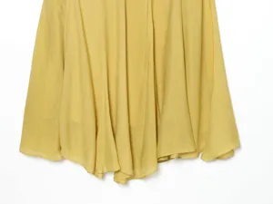 Yellow pleated long skirt fabric close-up, soft and flowy draped hemline design.