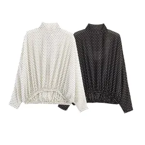 Detailed view of women's long sleeve high neck polka dot top in black and white colors.