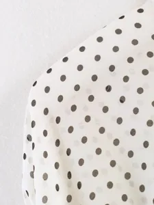 Close-up detail of elegant black and white polka dot fabric for women's stylish fashion apparel.
