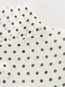 Close-up detail of white and black polka dot chiffon fabric collar and chic blouse texture.
