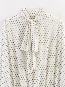 Detailed view of women's polka dot blouse featuring an elegant bow tie neck and long sleeves.