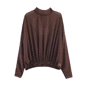 Detailed view of the brown polka dot long sleeve top featuring a chic mock neck and gathered hem.