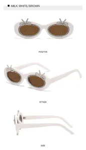 Schicke ovale Strass-Sonnenbrille mit Schleifen, milchweißer Rahmen und braune Gläser.