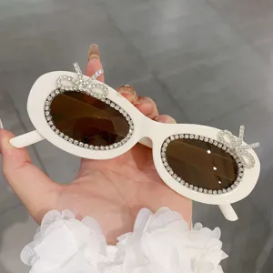 Schicke weiße ovale Sonnenbrille mit funkelnden Strass-Rändern und Kristall-Schleifen.