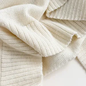 Primo piano dettagliato di un morbido tessuto in maglia bianco crema con delicata costina.