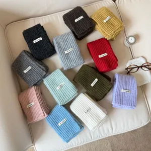 Detailed view of colorful knitted wool-blend winter scarves with small brand labels.