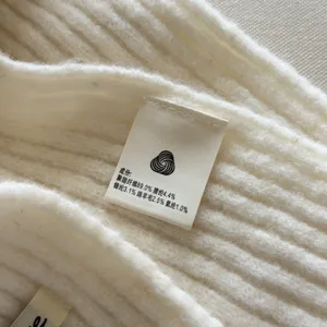 Close-up detail shot of soft knitted wool blend scarf fabric showcasing the care label.