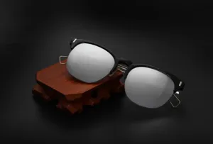 Detail view of stylish half-frame sunglasses with metallic hollow temples and reflective lenses.