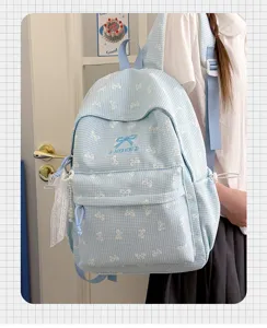 Sac à dos d'écolier à carreaux bleus avec nœuds brodés porté par un mannequin