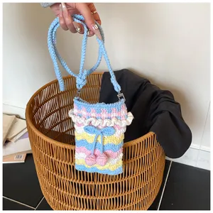 Detailaufnahme einer handgefertigten Häkel-Handytasche mit Kirsch- und Schleifenakzenten
