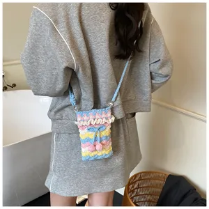 Detailansicht einer handgehäkelten Handytasche mit bunten Streifen und Kirschdekor am Modell