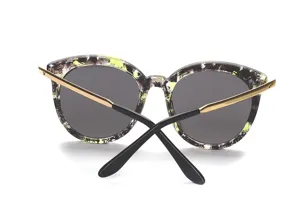Stylische Damen Sonnenbrille mit abstraktem Muster, goldenen Bügeln und dunklen Gläsern.