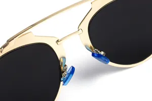Gouden metalen montuur zonnebril detailopname met donkere lenzen en blauwe neuspads