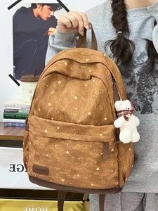 Detailansicht eines braunen Vintage-Schulrucksacks mit Sternenmuster und Bärenanhänger