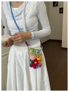 Petit sac à bandoulière floral fait main au crochet, porté dans un cadre artistique