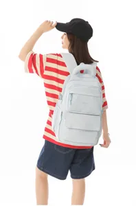 Back view of a student girl wearing a light blue large school backpack with embroidery.