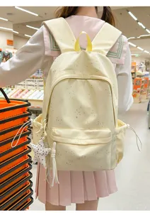Mochila escolar amarilla crema con estampado de estrellas vista desde la espalda