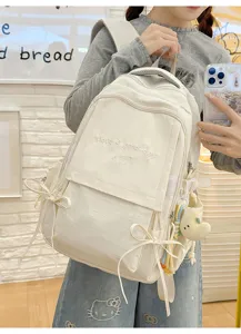 Sac à dos blanc cassé avec broderie 'Have a good day' porté par un mannequin dans un café