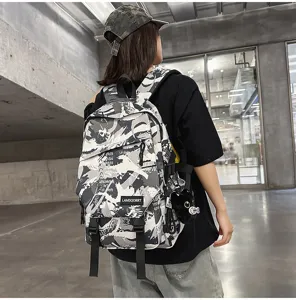 Rückansicht eines Schülers mit einem dunkelgrauen Graffiti-Rucksack mit Katzenanhänger