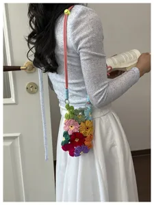 Vue détaillée d'un sac de téléphone portable en crochet fait main aux fleurs colorées.