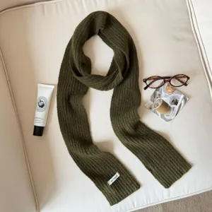 Close-up of dark green knit scarf with cozy texture and stylish flat lay lifestyle props.