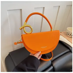 Nahaufnahme der orangefarbenen Satteltasche mit goldenem Metallring Griff im Detail.