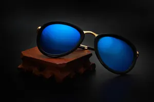 Detailopname van retro ronde zonnebril met blauwe spiegelende lenzen, zwart montuur en gouden brug.