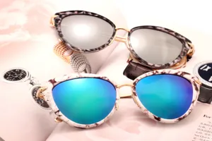 Close-up detail of fashionable cat-eye sunglasses with colorful reflective lenses and marble frames.