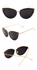 Detail view of trendy black cat-eye sunglasses with gold metal frames and dark lenses.