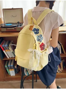 Detailansicht des süßen gelben Rucksacks aus Canvas mit bunter Blumenstickerei und weißer Schleife.