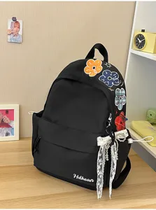 Detailansicht des schwarzen Rucksacks mit bunten Blumenstickereien und hübscher Spitzenschleife.