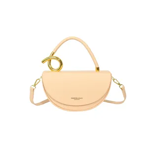 Detailansicht der eleganten Halbmond-Satteltasche in Beige aus Leder mit goldenem Griffring.