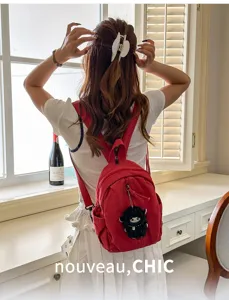 Detailansicht des roten Freizeit-Mini-Rucksacks aus Canvas mit süßem Plüsch-Schaf-Anhänger.