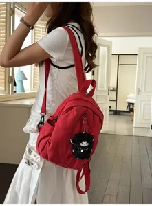 Roter Canvas Rucksack mit schwarzem Schaf Anhänger für Alltag Pendeln und Reisen.