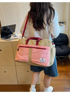 Female model carrying a large pink and khaki color-blocked travel bag over the shoulder.