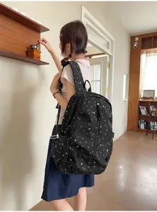 Dettaglio laterale di uno zaino nero con motivi a stelle indossato da una studentessa