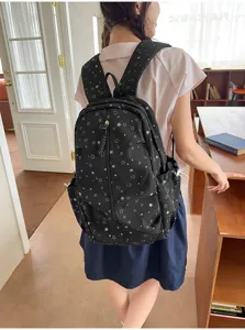 Vista posteriore di uno zaino nero con motivo a stelle indossato da una modella