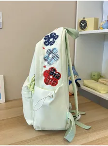 Nahaufnahme des hellgrünen Schulrucksacks mit niedlichen bestickten Blumendetails und Seitentasche.