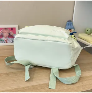 Detailansicht des hellgrünen Canvas-Rucksacks mit Riemen und Klappen-Stickerei-Design.