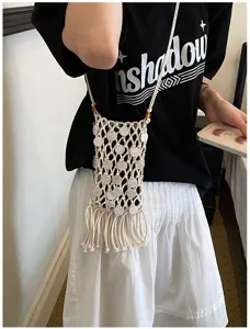 Detailed macro view of the bohemian woven tassel phone bag worn by a casual model