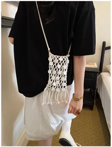 White bohemian woven crossbody phone bag with fringe and shell disc accents on model