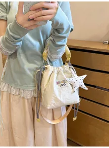 Dettaglio di un sacchetto a secchiello bianco in stile giapponese con ciondolo a stella e manico