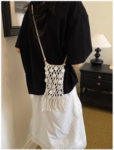 Detail of hand-woven white tassel phone bag showing hollow-out knit and shell discs