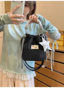 Dettaglio di una borsa a secchiello nera tenuta da una ragazza con maglione celeste