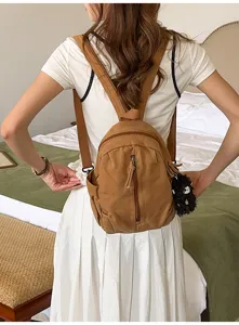 Detailansicht des braunen Canvas Minirucksacks am Model im Schlafzimmer, stylisch casual.