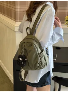 Detailansicht des kleinen Canvas-Rucksacks in Dunkelgrün mit Plüschanhänger und Taschen.